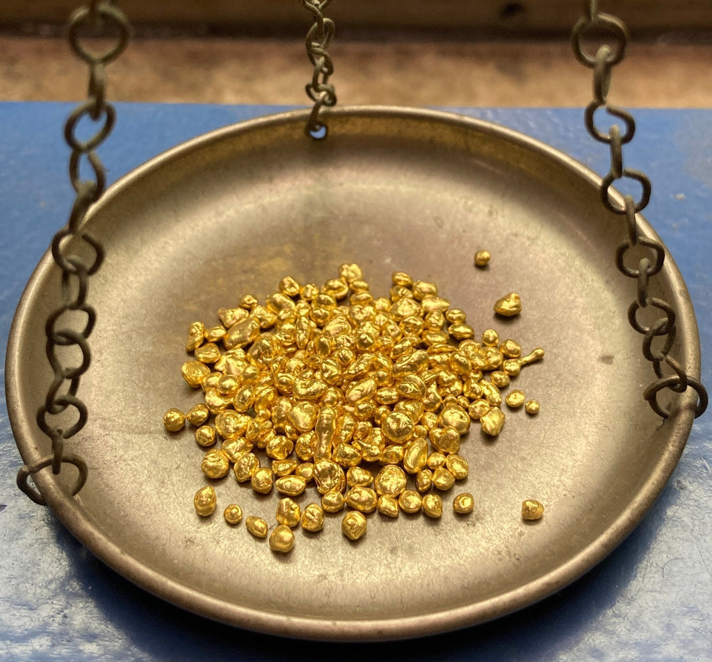 Close up of 24k gold grains on balance scale before alloying for handmade ancient style jewelry by Alexis Menten