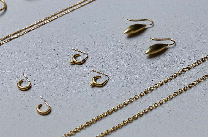 Collection of three pairs of 22k gold earrings handmade by Alexis Menten in an ancient style displayed next to two chains