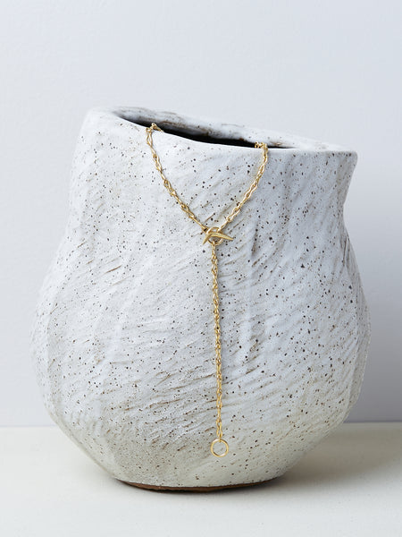 Ancilia Chain by Alexis Menten with handmade 20k gold figure eight ancient style links shown as a lariat on a ceramic vase