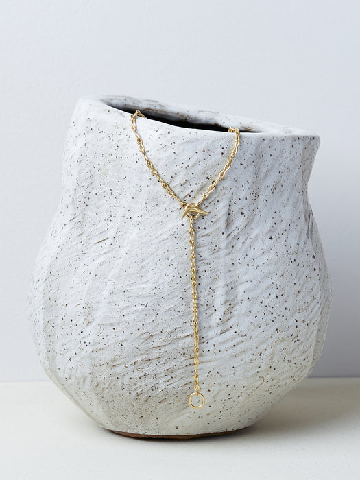Ancilia Chain by Alexis Menten with handmade 20k gold figure eight ancient style links shown as a lariat on a ceramic vase