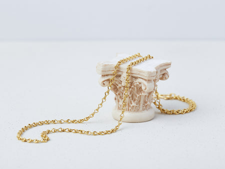 Apeiron Chain by Alexis Menten with intricate 22k gold links handmade in an ancient style displayed on a small column capital