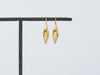 Cylichna Earrings by Alexis Menten with 22k gold tapered cylinders handmade in an ancient style shown hanging on a metal bar