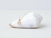 Lunula Necklace by Alexis Menten with a 22k gold crescent shaped pendant handmade in an ancient style shown on a seashell