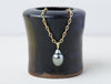 Nuru Chain handmade by Alexis Menten with an ancient style 20k gold chain and gray South Sea pearl pendant on a small vase