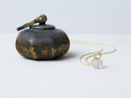 Omphalos Necklace by Alexis Menten with an ancient style morganite melon bead pendant next to a metal object of similar shape