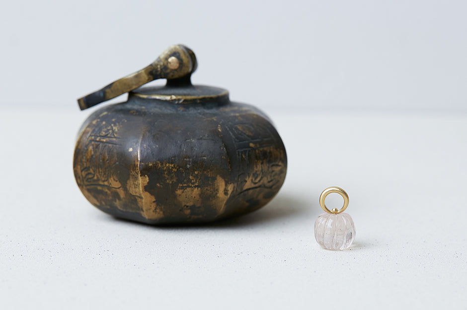 A pendant handmade by Alexis Menten with an ancient style melon bead and 20k gold bail next to an object of similar shape