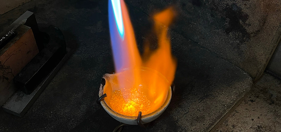 Close up of Alexis Menten alloying 22k gold in a crucible with a handheld torch