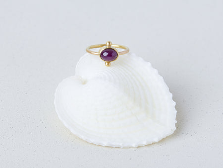 Satnal Ring by Alexis Menten handmade in an ancient style with 22k gold, a ruby, and two granules shown on a seashell