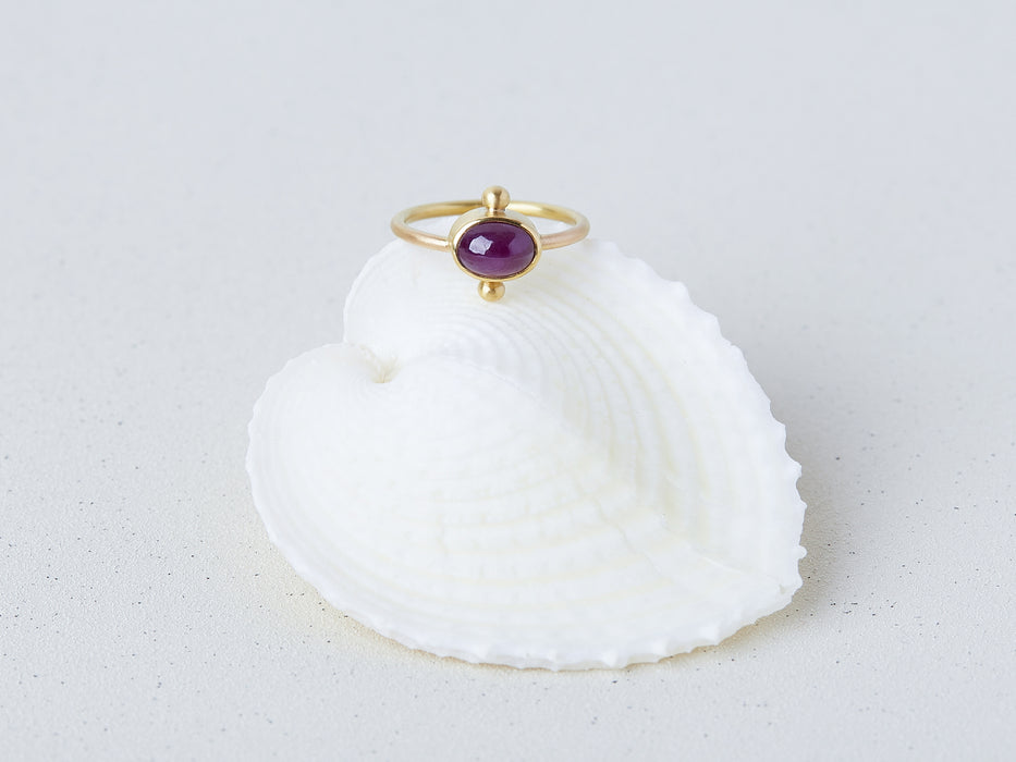 Satnal Ring by Alexis Menten handmade in an ancient style with 22k gold, a ruby, and two granules shown on a seashell