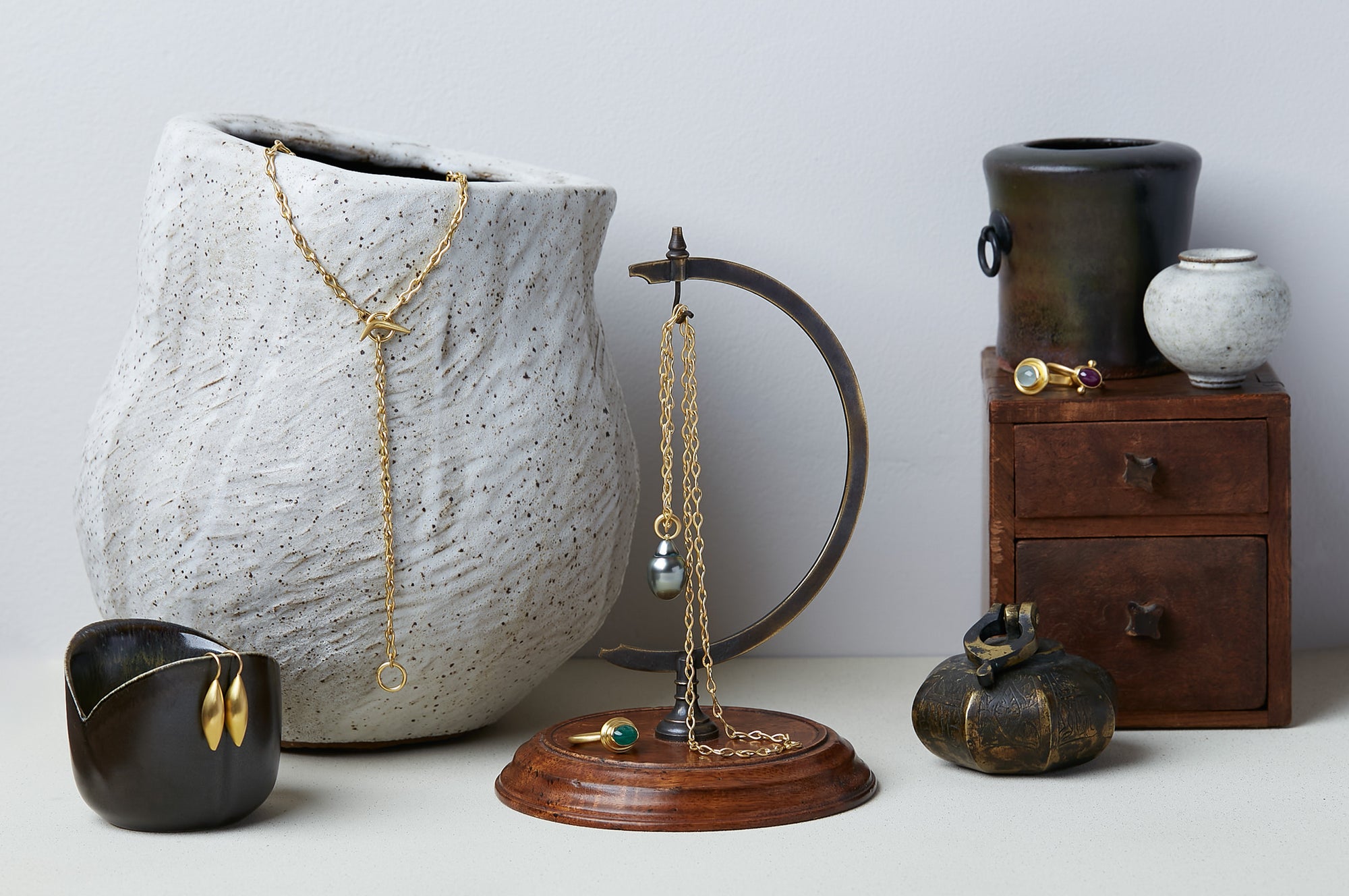 Collection of ancient style jewelry handmade by Alexis Menten on ceramic vessels, an antique wood box, other unique objects